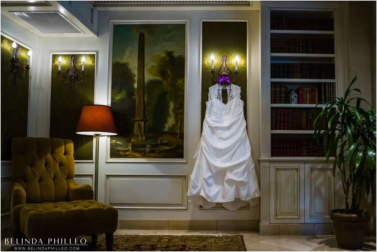 Bride's wedding dress hangs in the library style lobby at Ayres Hotel Seal Beach