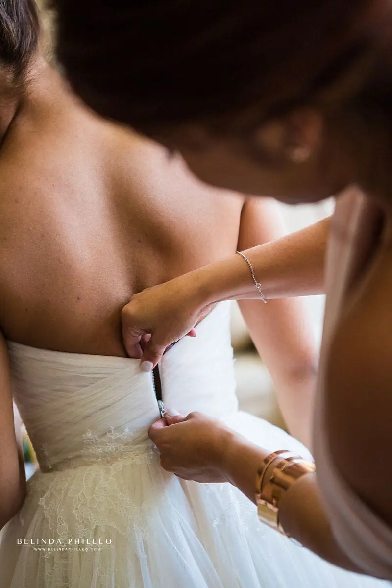 Mother of the bride zips up the bride's gown 