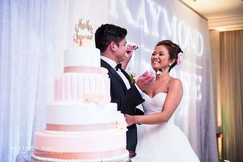 Pink and white tiered wedding cake with buttercream frosting and pink roses