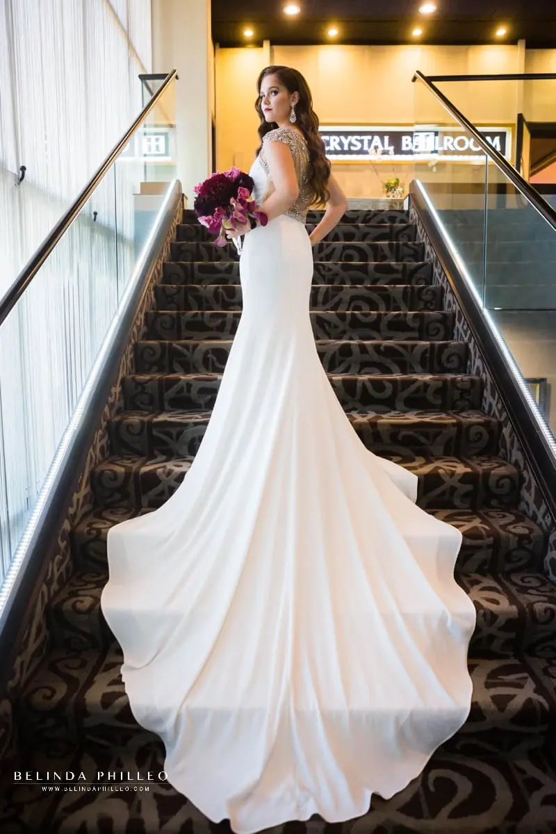 Bride shows of her Calla Blanche bridal gown on the staircase at The Hills Hotel Laguna