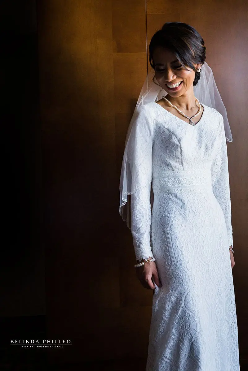 Glowing bride shows off her Modest by Mon Cheri wedding gown from The Hitching Post