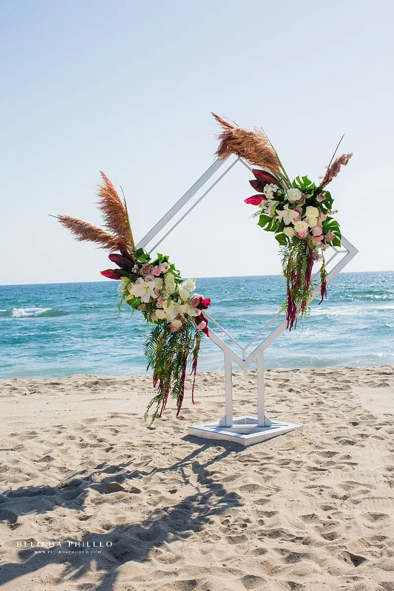 Bespoke wedding ceremony arch in Huntington Beach, CA created by Serenade of Flowers. Photo by Belinda Philleo