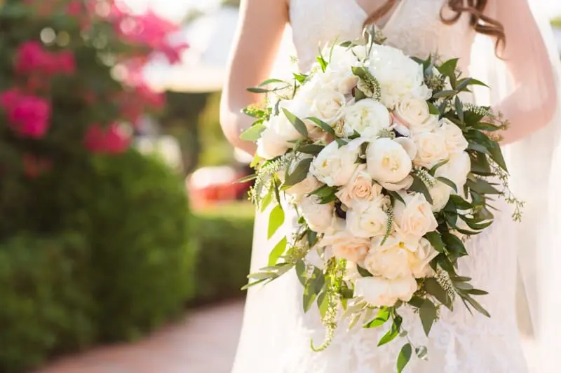 Bride shows off her dramatic bouquet of white peonies and blush roses at Hummingbird Nest Ranch
