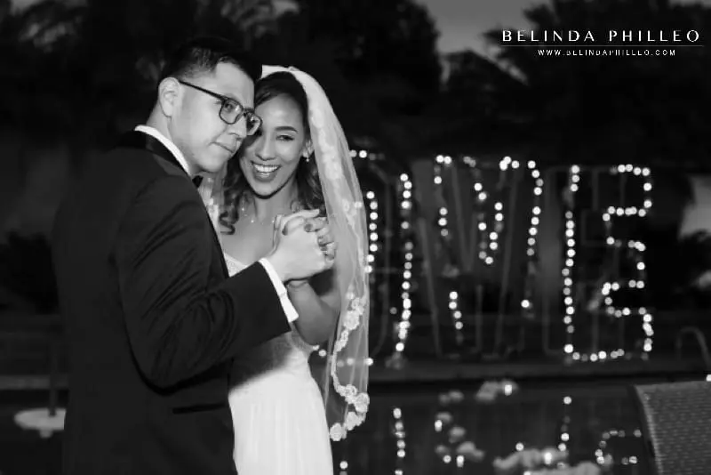 Bride and groom share first dance in front of giant LOVE marquee sign at their backyard wedding in Orange County, CA