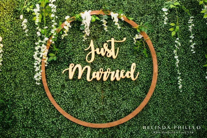 Wooden just married sign on plant wall at backyard wedding