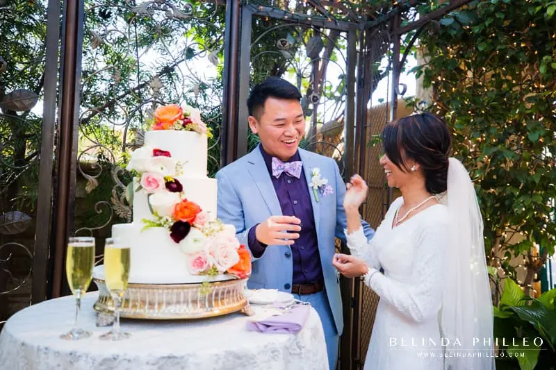 Newlyweds cut their cake at their outdoor wedding reception at The Hacienda in Santa Ana, CA