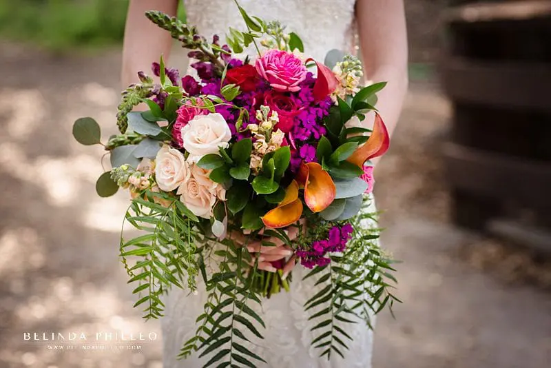 Vibrant and tropical bridal bouquet with orange, pinks, fuchsia, and greenery.