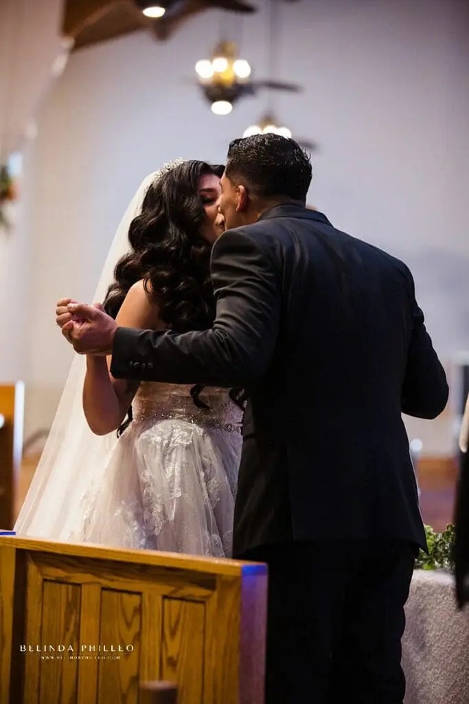 Couple shares a first kiss while holding hands during their wedding in Southern California. Photography by Belinda Philleo