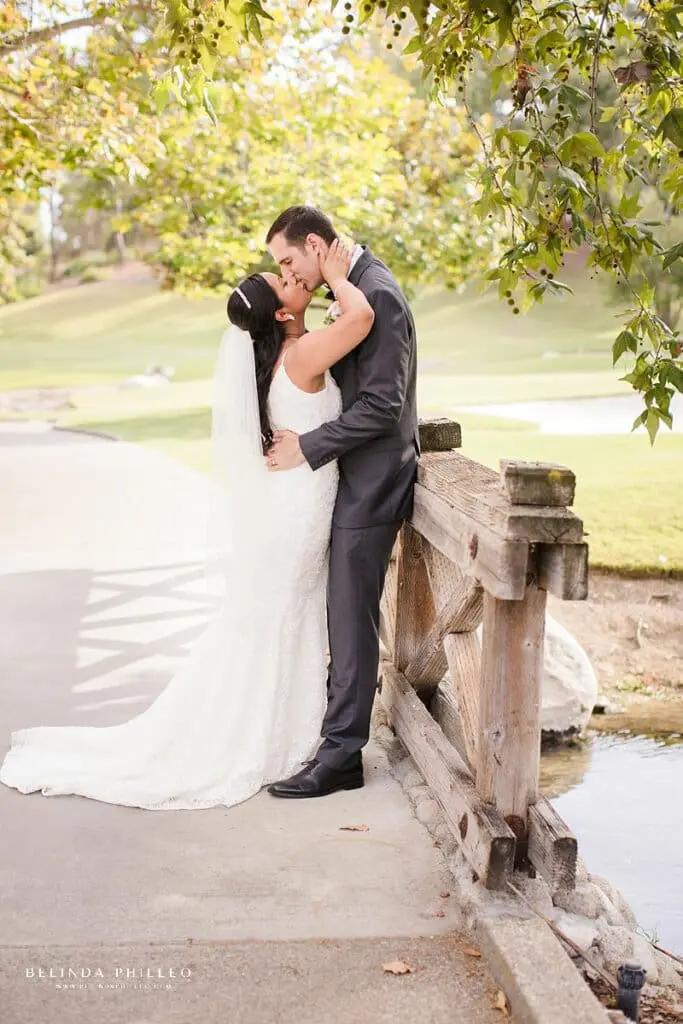 Bride and groom share a kiss on bridge at Coyote Hills Golf Course wedding in Fullerton, CA.