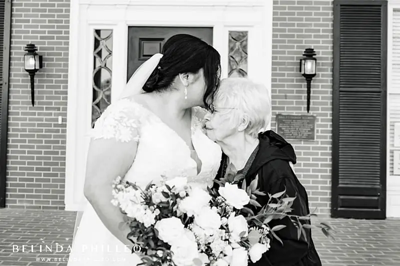Wedding photos with parents and grandparents. Bride kisses her grandma on her wedding day.