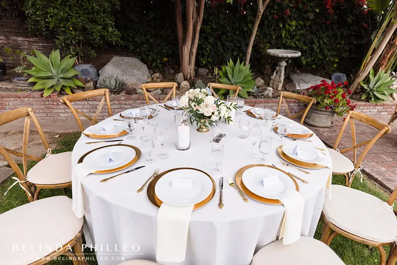 Closeup of wedding reception table with flowers and gold cutlerly