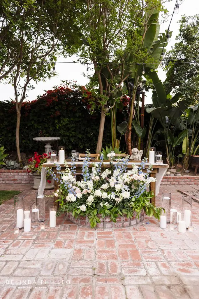 Sweetheart table decorated with flowers and candles at a backyard wedding