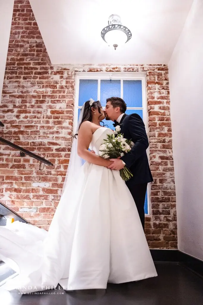bride and groom share a kiss at the top of a stairwell