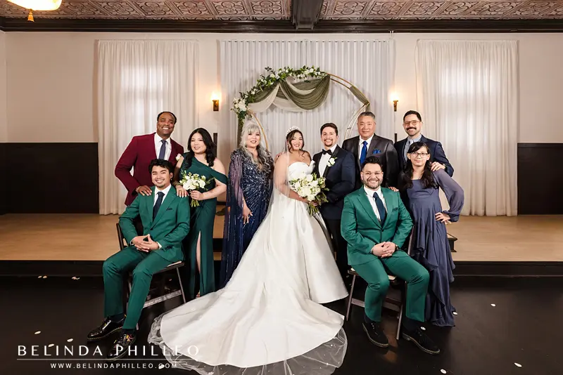 A family portrait after the wedding ceremony where some family members are standing and some are seated.