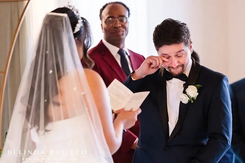 Groom wipes away a tear as the bride reads her vows