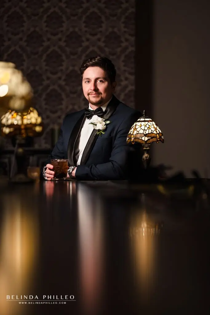 Portrait of a groom with his cocktail at the bar