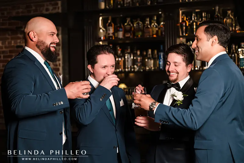 A groom and his groomsmen toast and cheers at the bar