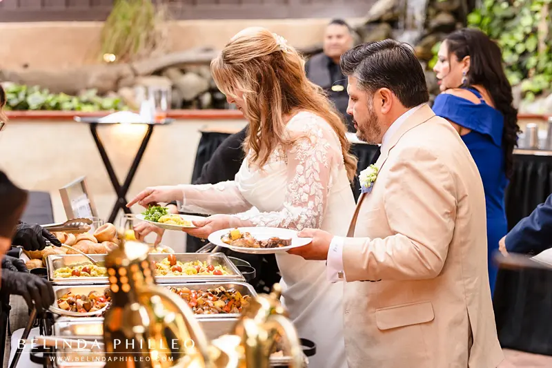 Bride and groom fill their plates at a backyard buffet