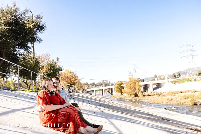 Couple cuddles and shares a laugh while sitting along the LA river