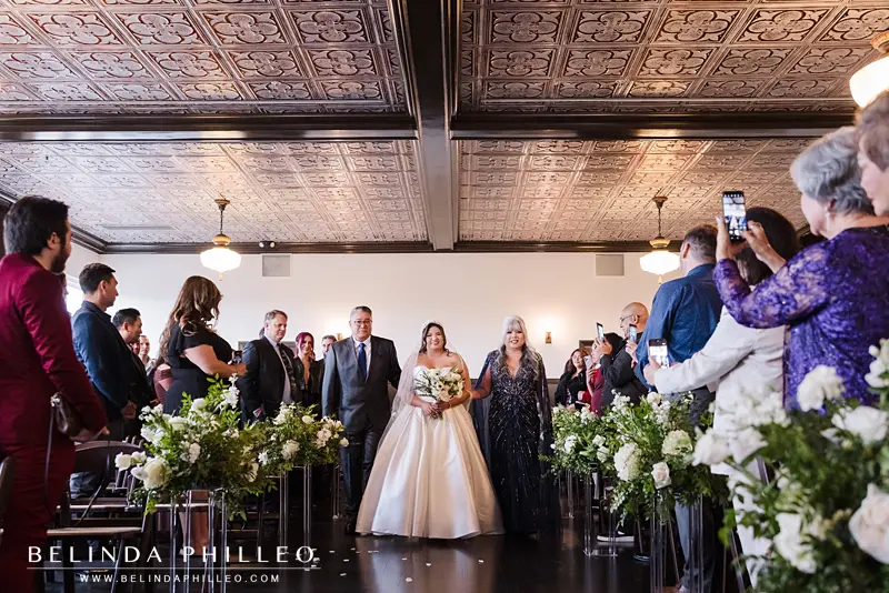 The bride is escorted down the aisle by her parents