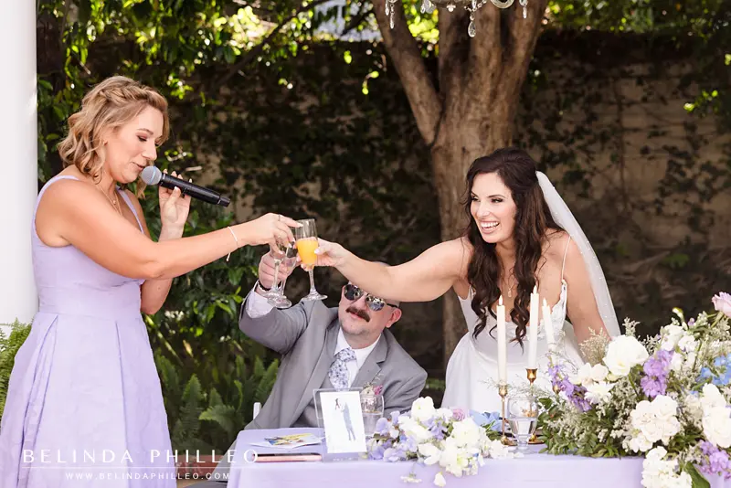 Newlyweds toast with the maid of honor during their wedding reception