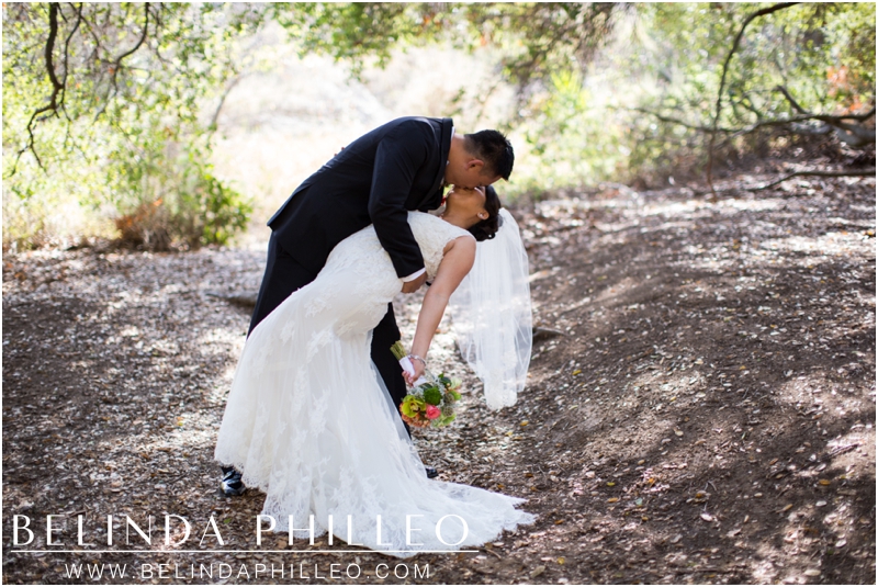 Groom dips and kisses his bride in Malibu, CA