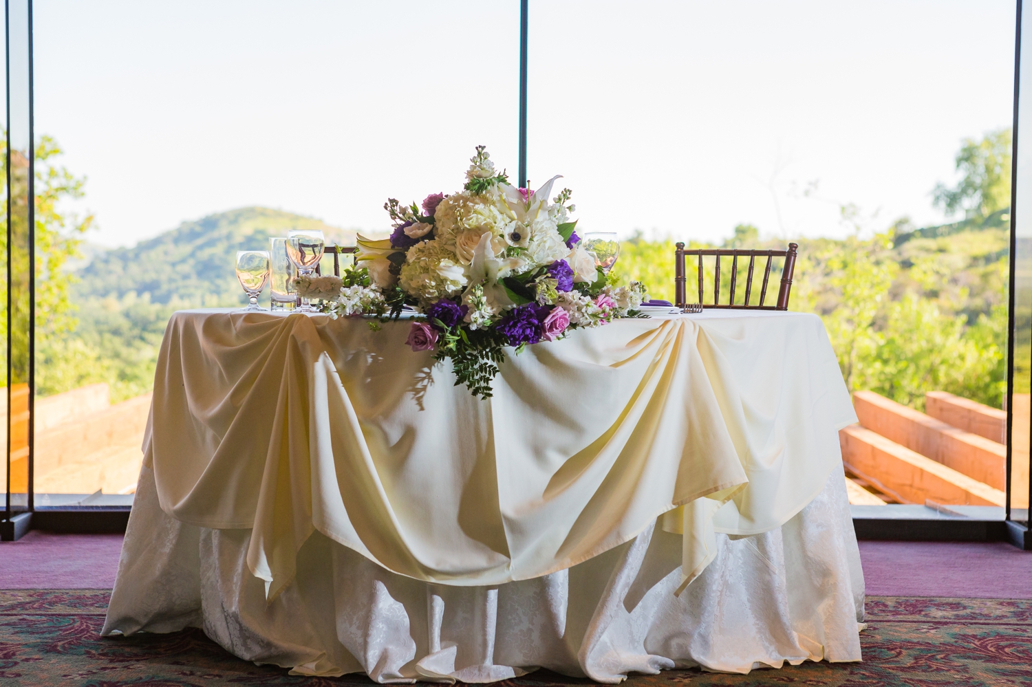 White and ivory sweetheart table with white and purple flowers at Dove Canyon Golf Club wedding reception