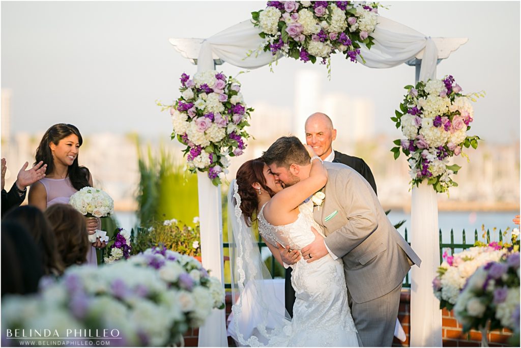 Bride and groom share their first kiss at The Reef Restaurant, Long Beach, CA. Photography by Belinda Philleo.
