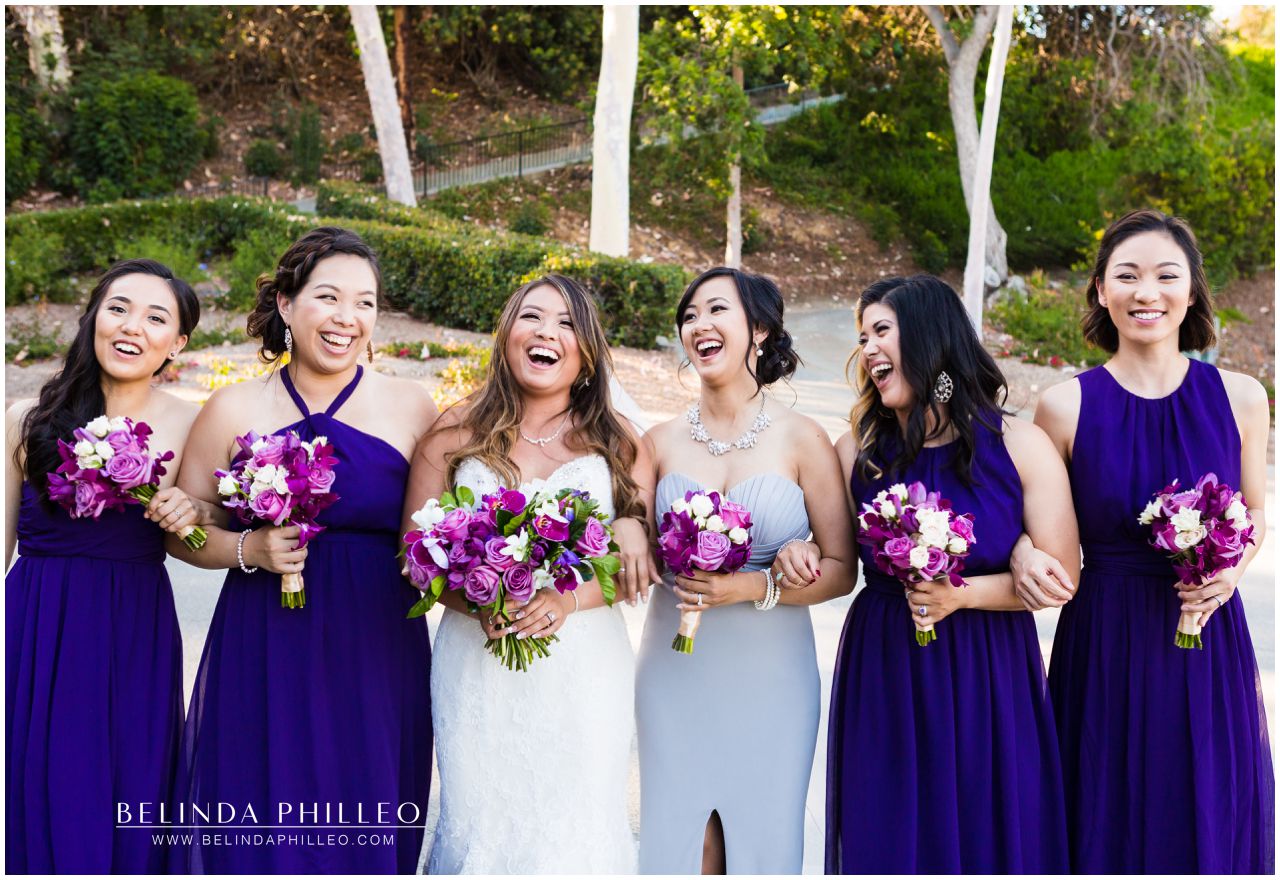 Bride and her bridesmaids in purple bridesmaid gowns share a laugh at Friendly Hills Country Club wedding