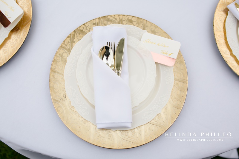 Backyard wedding reception table with gold chargers and serveware