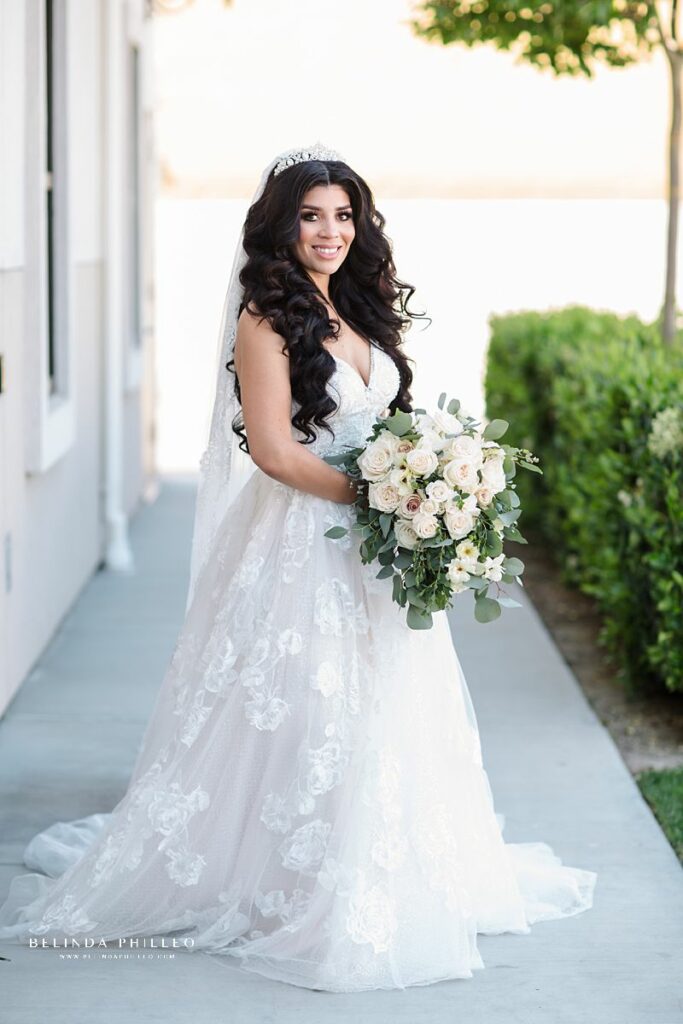 Bride shows off her Vneck ballroom bridal gown with white tulle florals and an all white bridal bouquet at wedding in Orange County, CA. Photography by Belinda Philleo