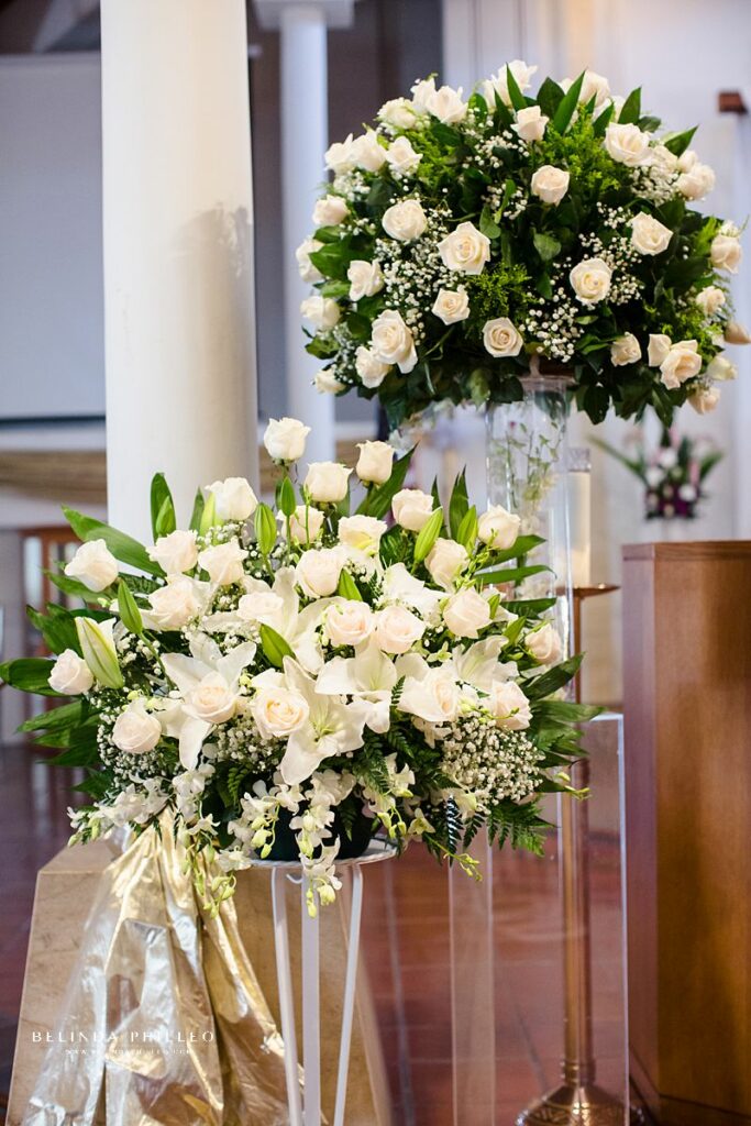 Large floral arrangements for wedding in Southern California. Large bouquets of white roses, babies breath, while lilies and ferns decorate church for wedding ceremony. Photography by Belinda Philleo