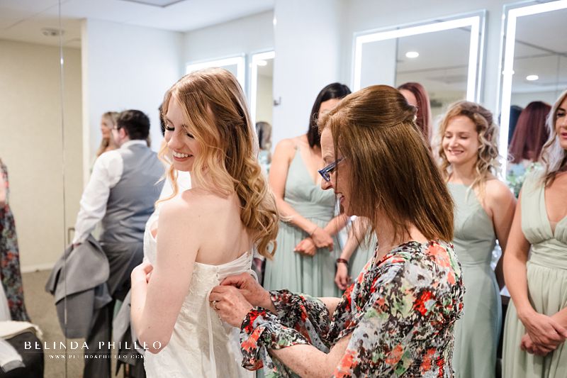 Bride is helped to get into her dress by her mother in the Bridal Suite at JACCC in Los Angeles, CA 