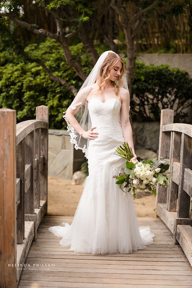 Bride shows off her Oleg Cassini CWG926 gown and V402 Corded Lace edge fingertip veil from David's Bridal at JACCC garden wedding in Los Angeles, CA