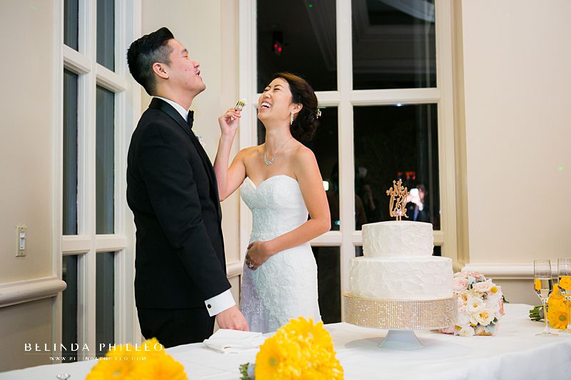 Newlyweds laugh while cutting their cake at Summit House wedding reception, Fullerton, CA