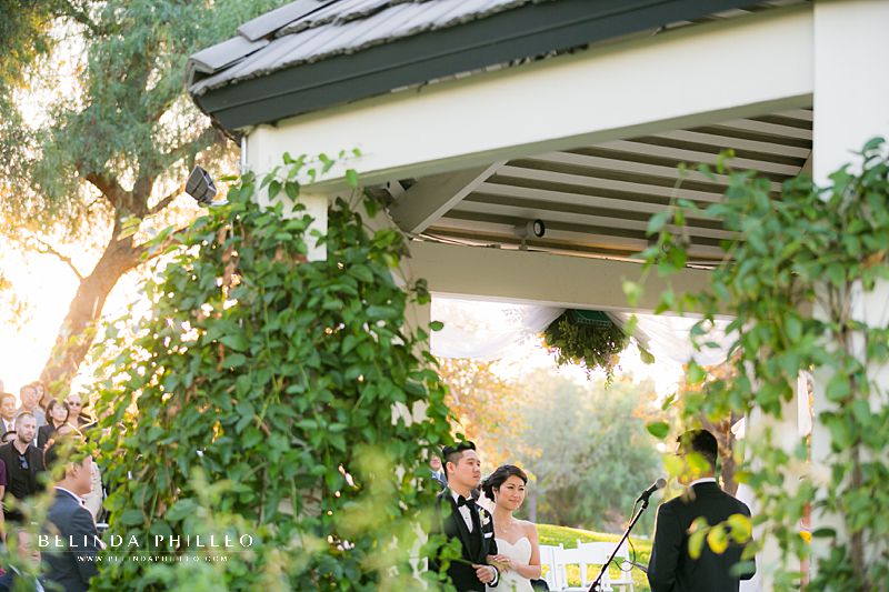 Bride and groom stand under the gazebo during Summit House wedding ceremony in Fullerton, CA